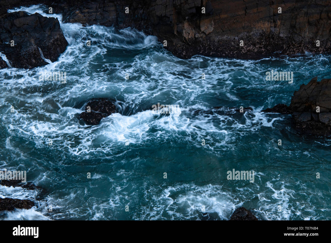 Onde che si infrangono sulle rocce Foto Stock