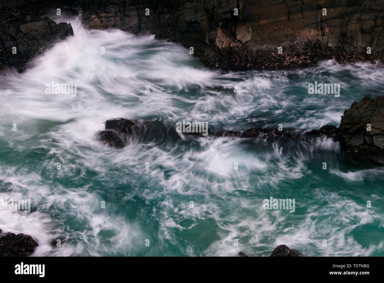 Onde che si infrangono sulle rocce Foto Stock