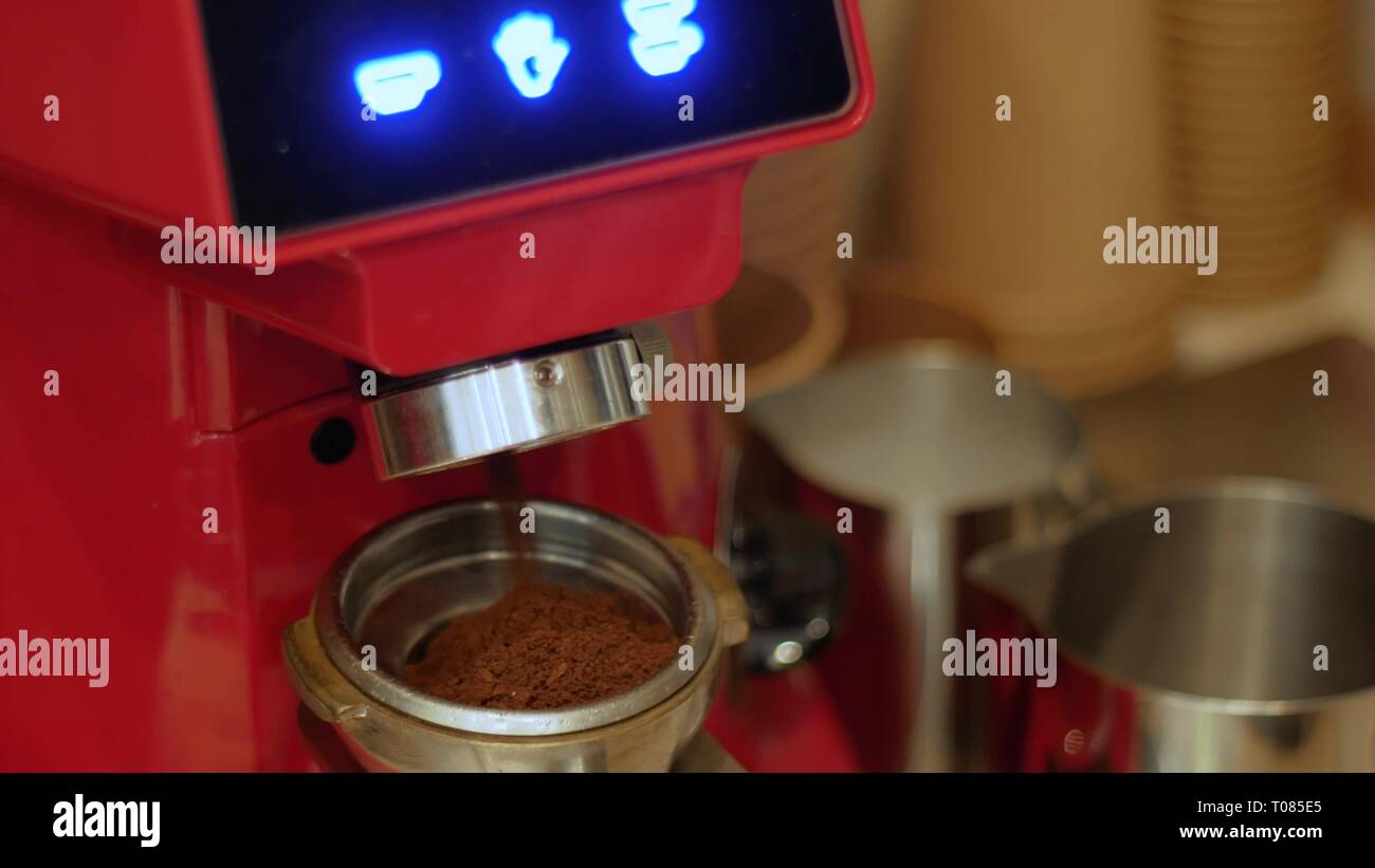 Una macchina elettrica per caffè macinacaffè macina caffè tostato fagioli in un supporto filtro Foto Stock