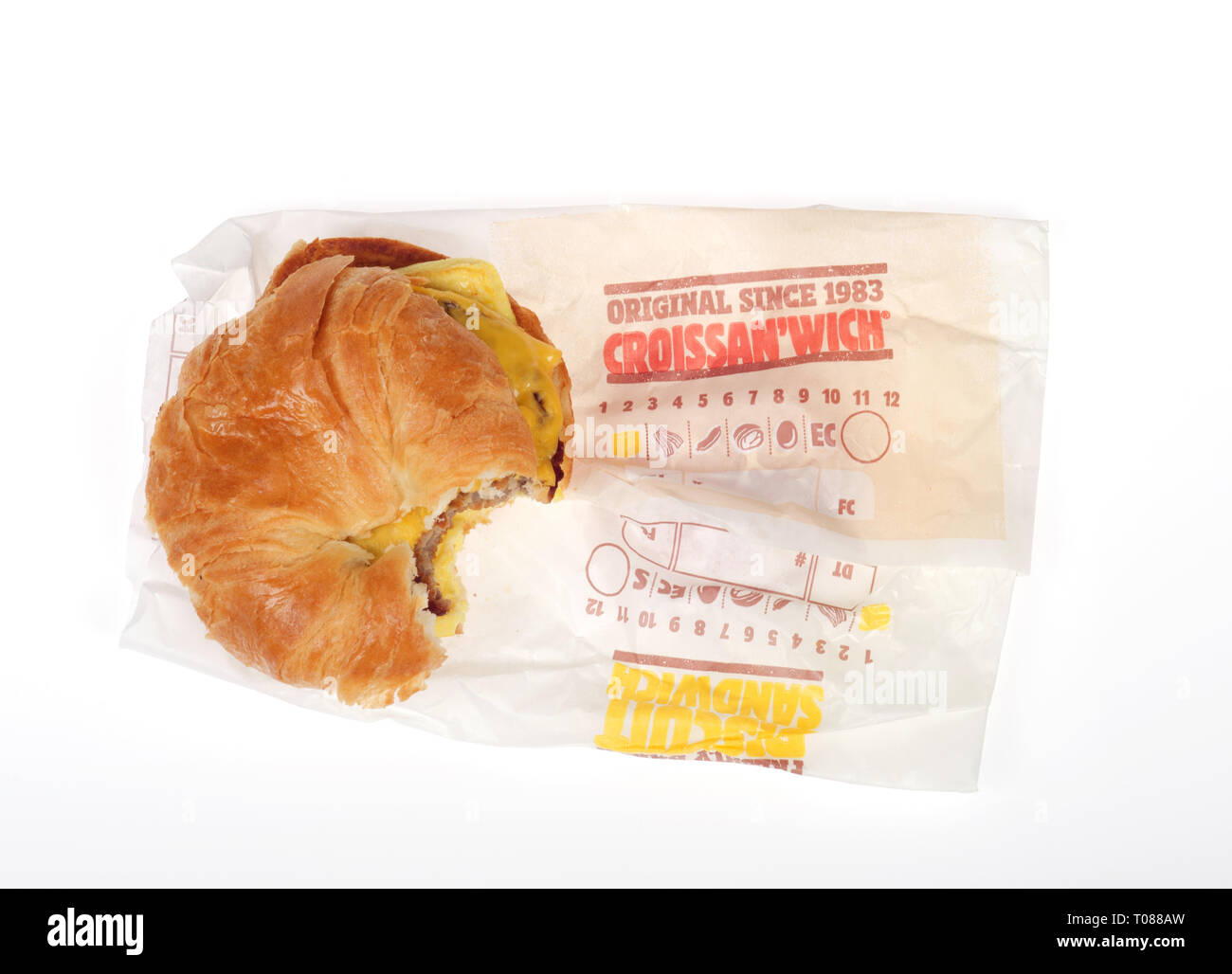 Burger King salsiccia, uova e formaggio croissant Croissan'quali con morso prelevato e wrapper su sfondo bianco Foto Stock