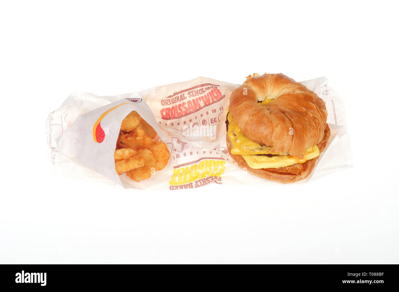 Burger King salsiccia, uova e formaggio Croissan"quale hash e marroni con involucri su sfondo bianco Foto Stock