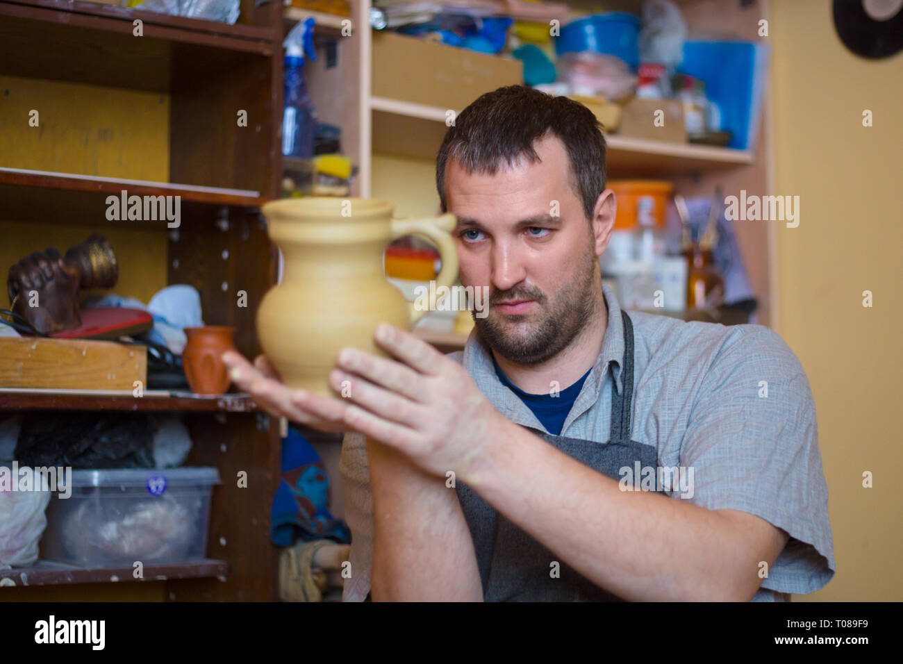 Maschio professionale potter esaminando vaso di terracotta nel laboratorio di ceramica, studio. Creazione, artwork e concetto di fatti a mano Foto Stock