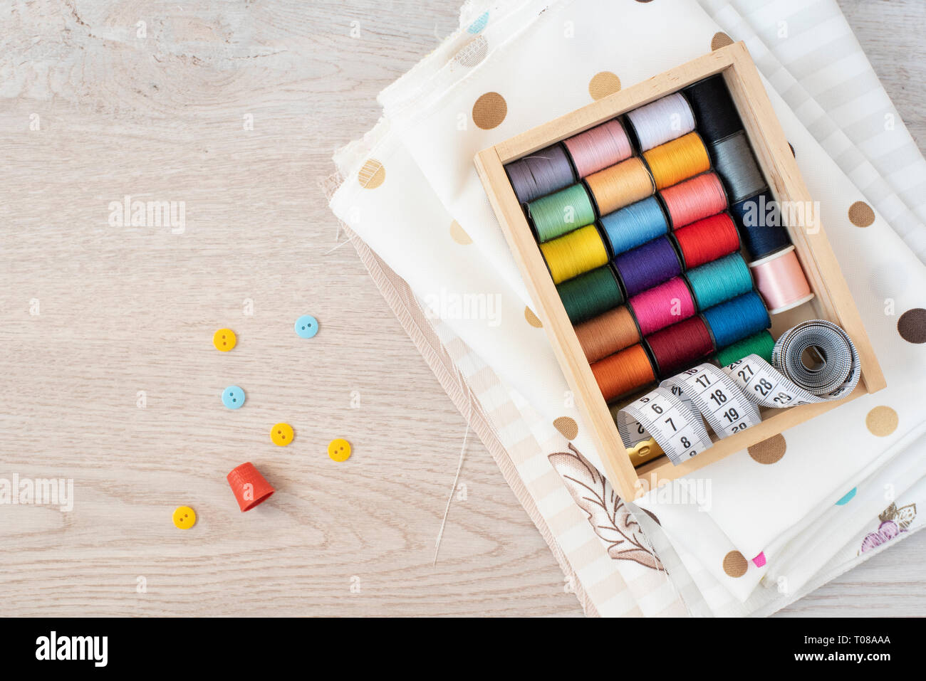 Composizione con fili di cucitura, tessuti e accessori su sfondo di legno, vista dall'alto Foto Stock