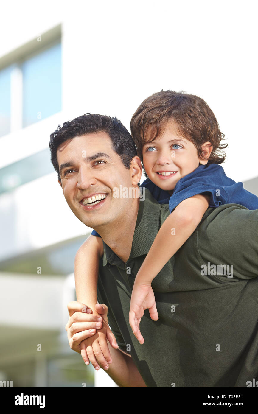 Padre Felice porta il suo piccolo figlio di piggyback sulla sua schiena Foto Stock