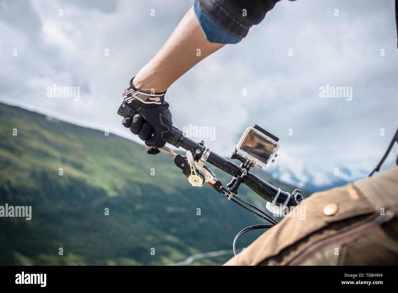 Giovane uomo su mountain bike dotate di azione della telecamera video. Colpo al passaggio Furker, alpi svizzere, in estate. Foto Stock