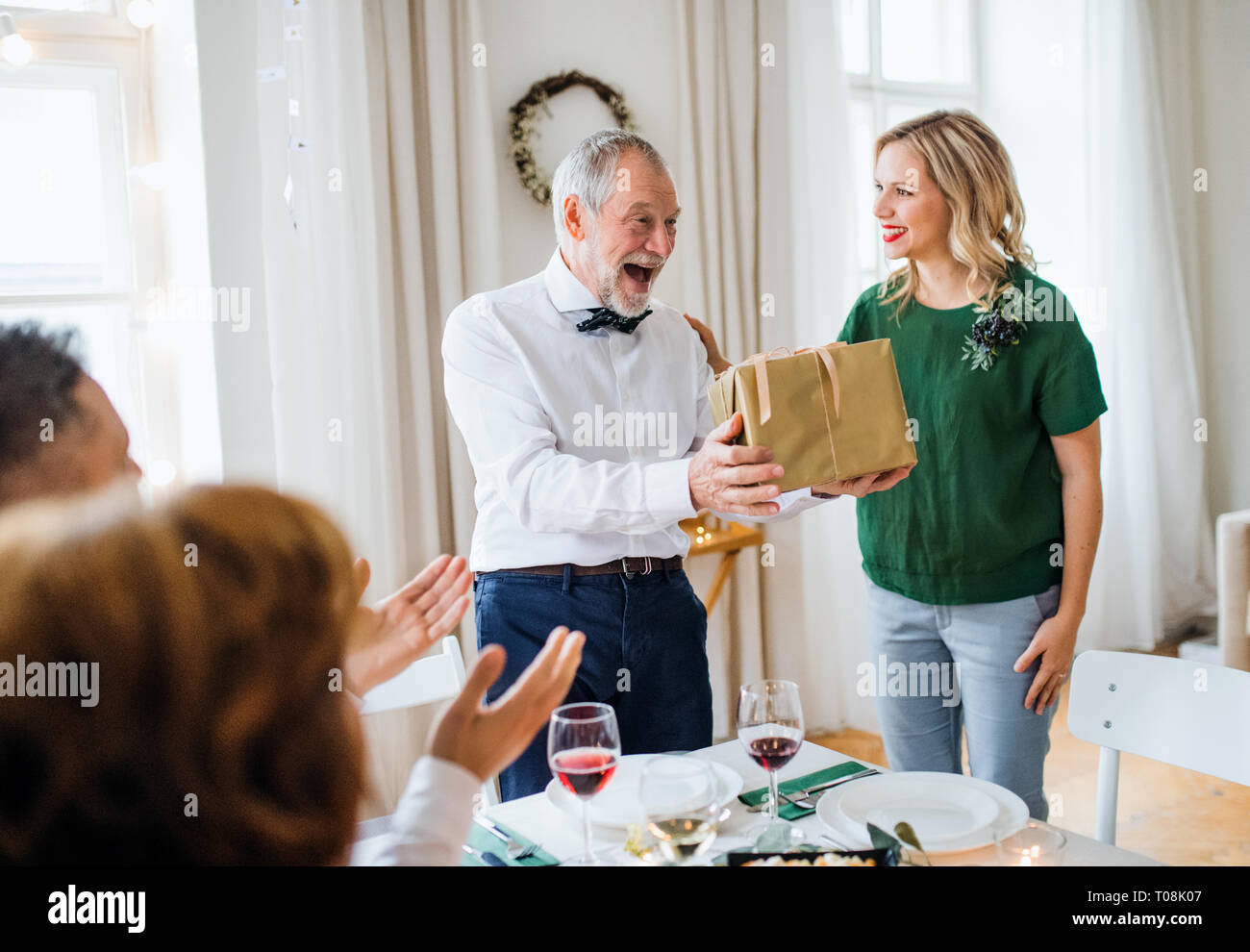 Giovane donna dando un dono a suo nonno sulla parte interna. Foto Stock