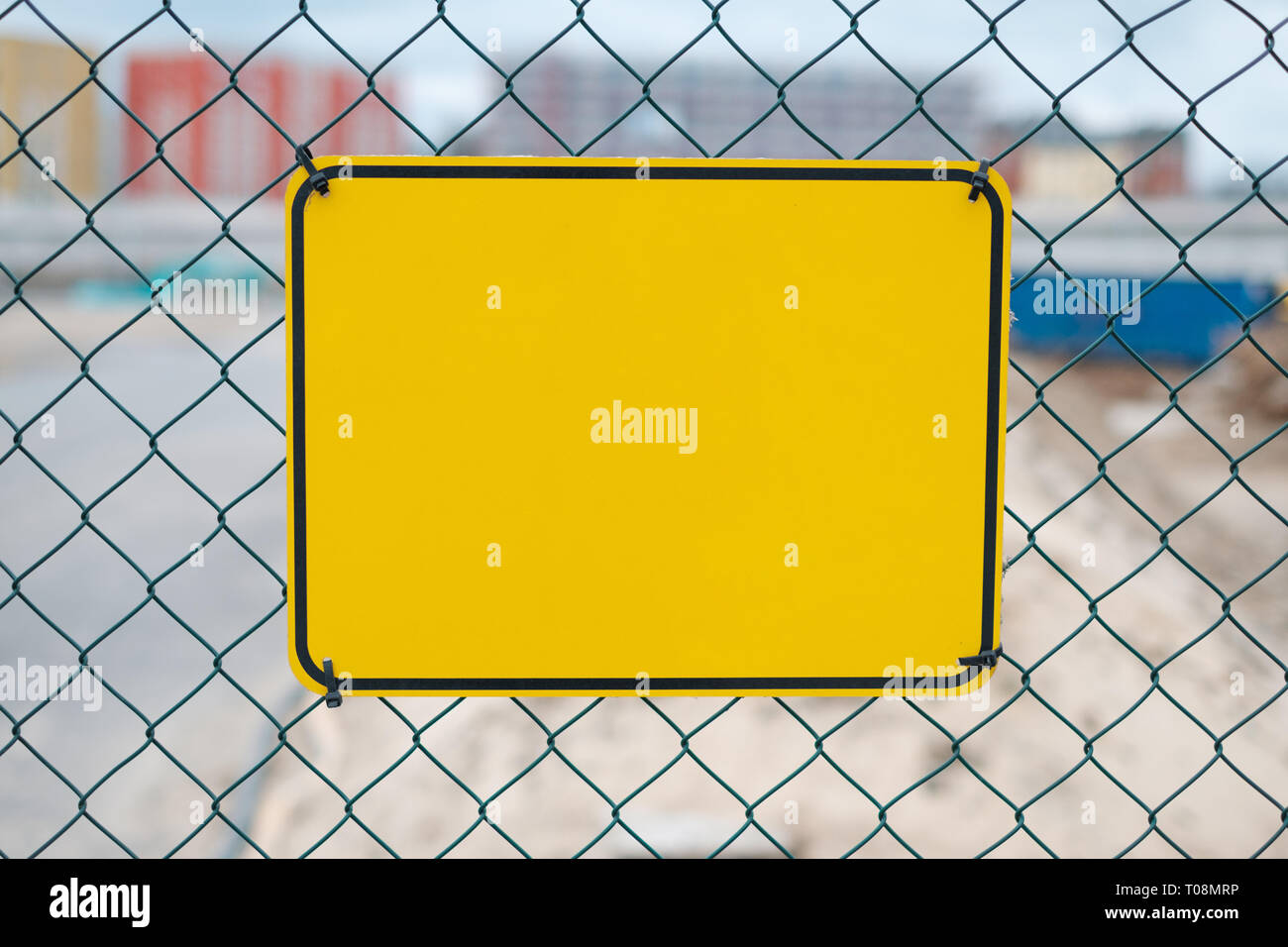 Blank cartello giallo sulla costruzione di recinzione del sito - segno di avvertimento mockup Foto Stock
