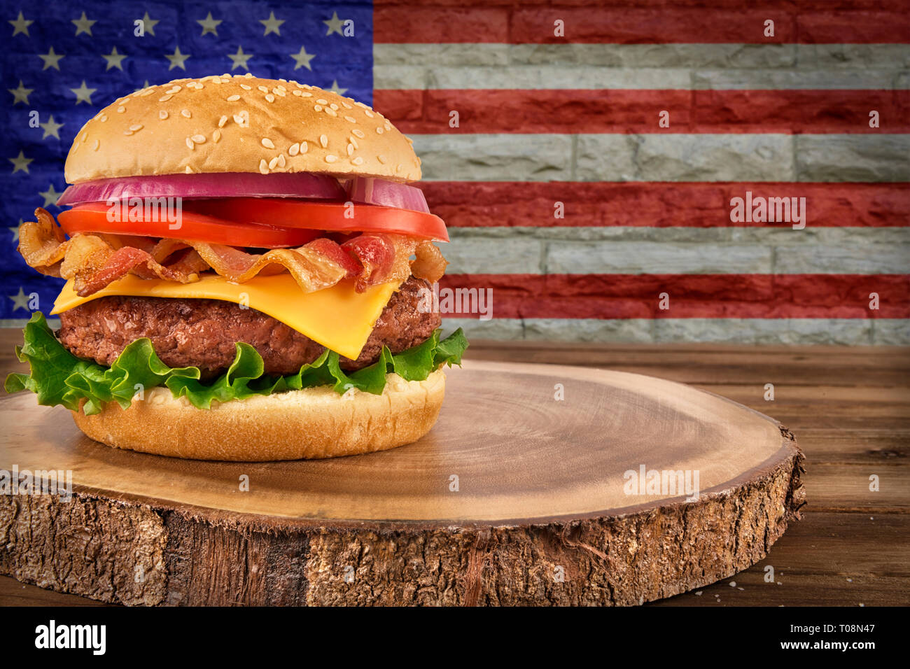 Cheeseburger con bacon. Bandiera degli Stati Uniti su un muro di mattoni in background. Foto Stock