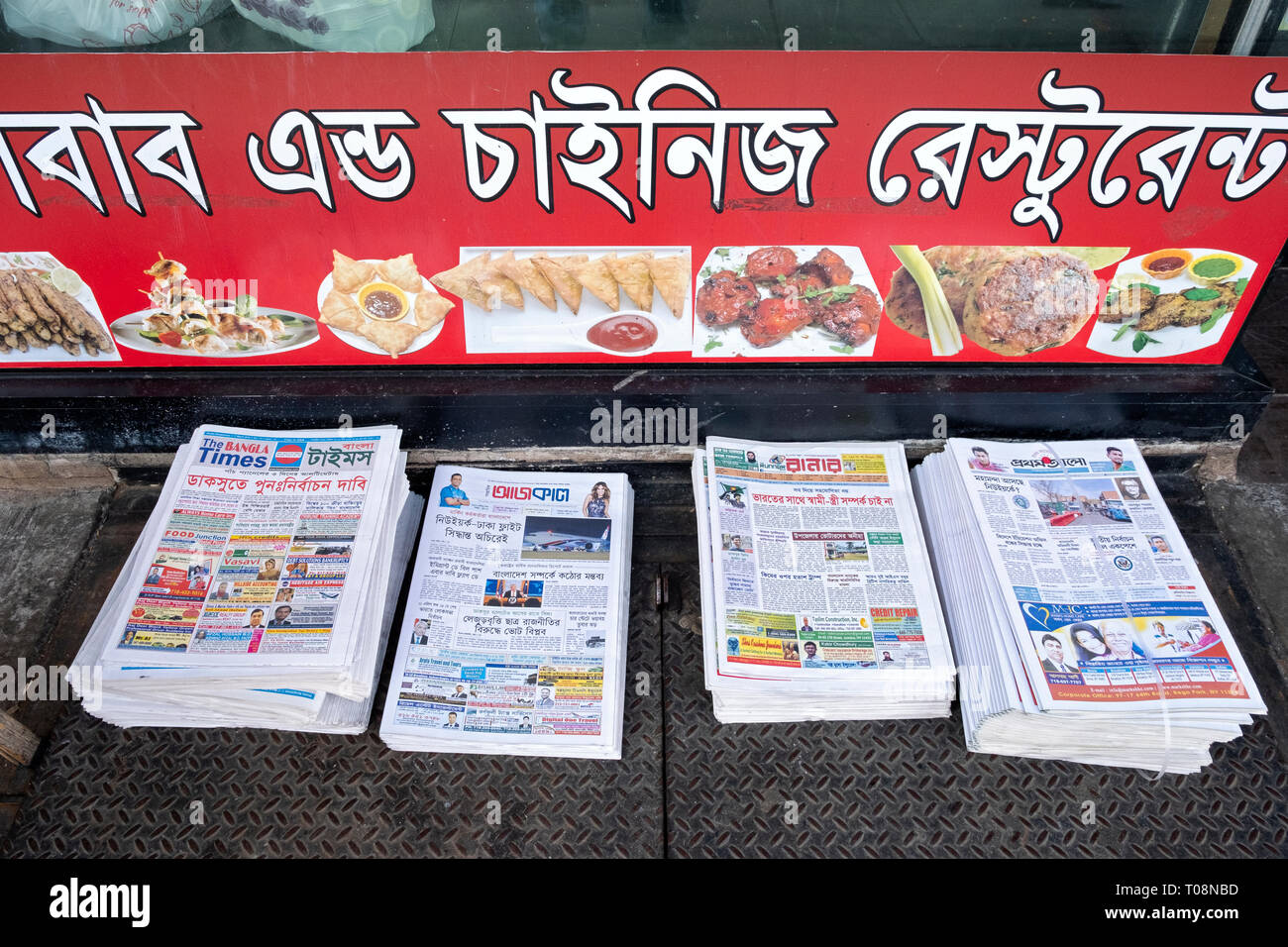 Pile di Begali gratuita quotidiani impilati al di fuori di un Bangladesh ristorante sulla 74a Strada di Jackson Heights, Queens, a New York City Foto Stock