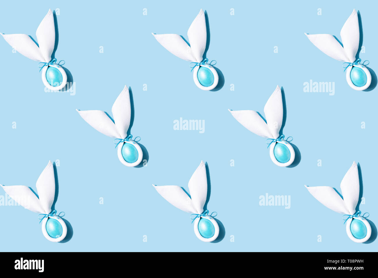 Modello realizzato del coniglietto di Pasqua le orecchie in bianco igienico con uovo su sfondo blu. In stile minimale easter card concept. Foto Stock