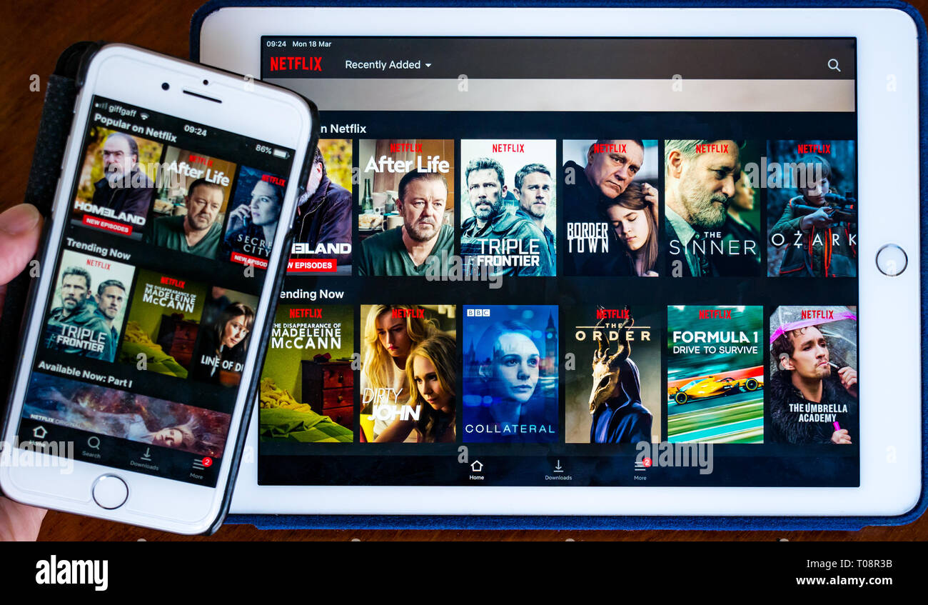 Schermo del telefono cellulare e schermo del dispositivo tablet che mostra l'app Netflix sullo schermo con i titoli di selezione dei film Foto Stock