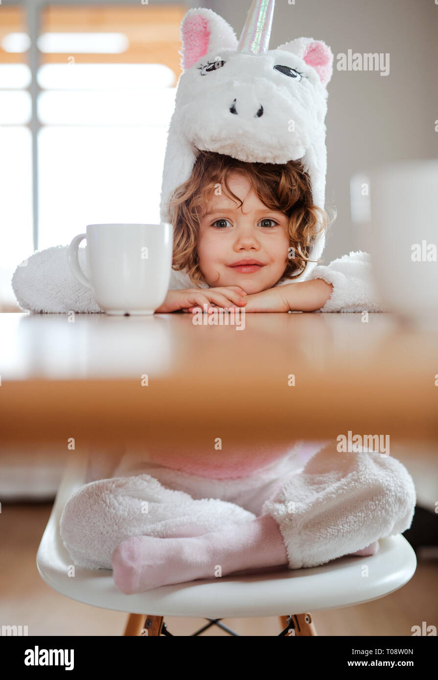 Un ritratto di bambina in maschera unicorno seduti a tavola a casa Foto  stock - Alamy