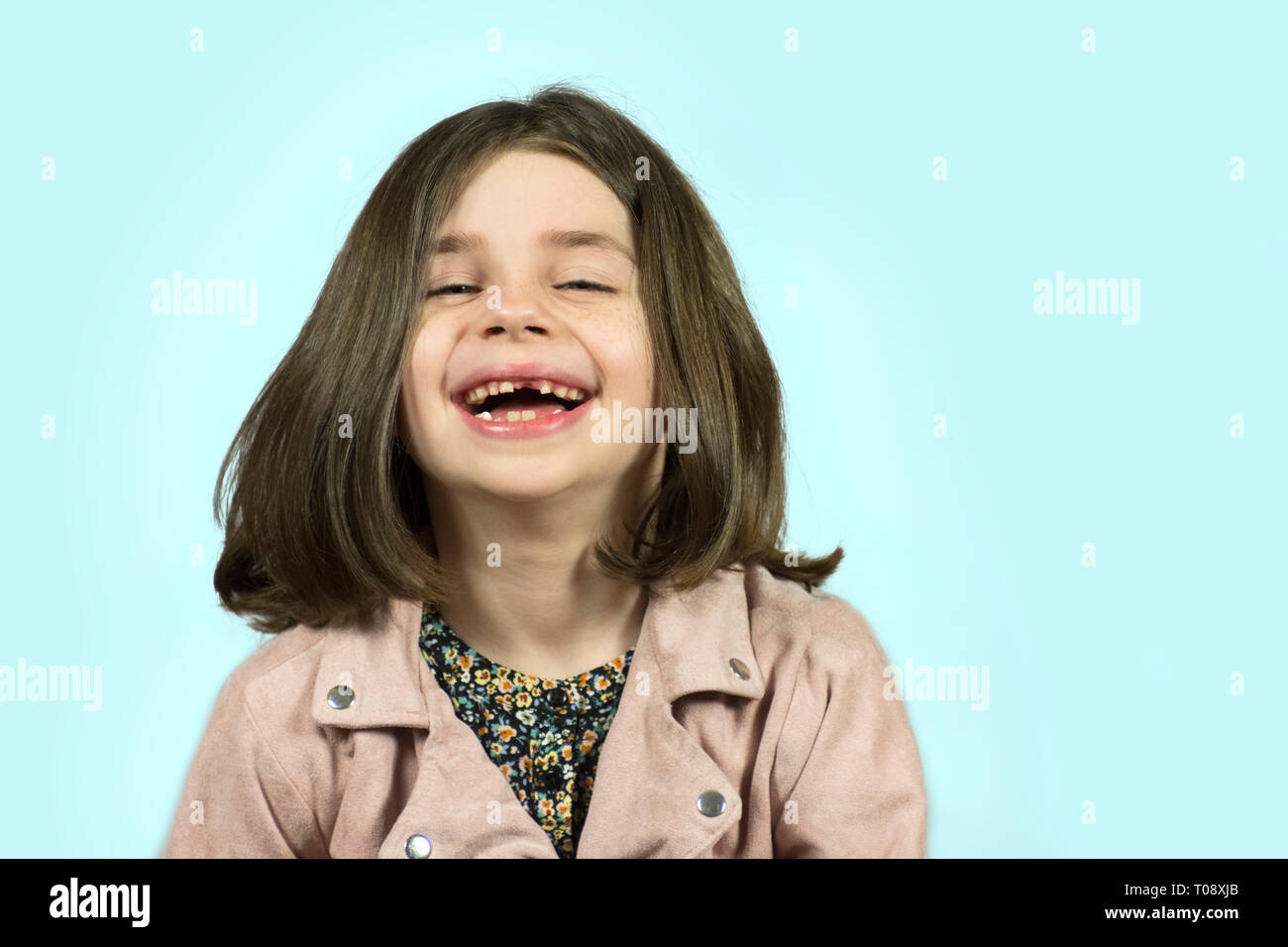 Bambina con denti mancanti di ridere con sfondo blu Foto Stock