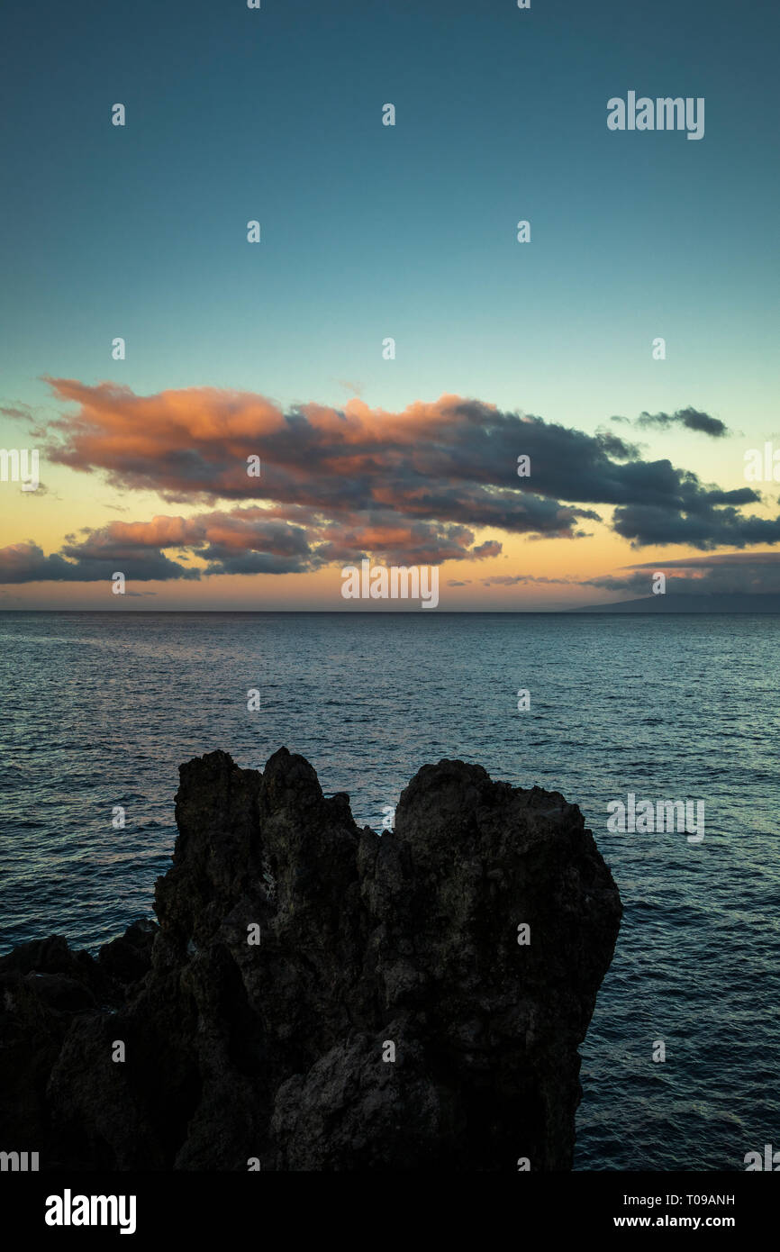 Nuvole sopra l'atlantico rosso acceso dall'alba con l'isola di La Gomera all'orizzonte, guardando ad ovest da Playa San Juan con la roccia vulcanica forma Foto Stock