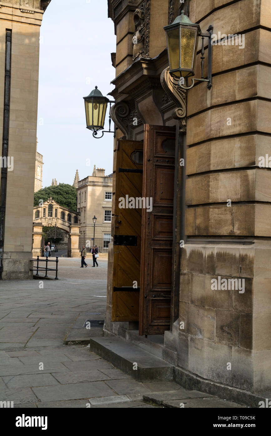 La porta principale di ingresso al Sheldonian Theatre in Broad Street, Oxford, Oxfordshire,la Gran Bretagna. In fondo è il Ponte dei Sospiri Foto Stock