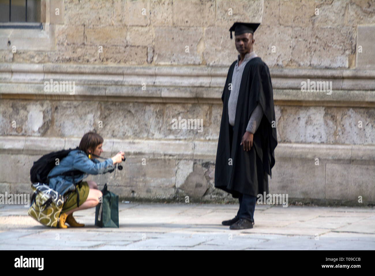 Un nero Oxford University studente in completo abito di graduazione e scheda mnotar fotografato dal suo amico di Oxford, Oxfordshire,la Gran Bretagna. Foto Stock