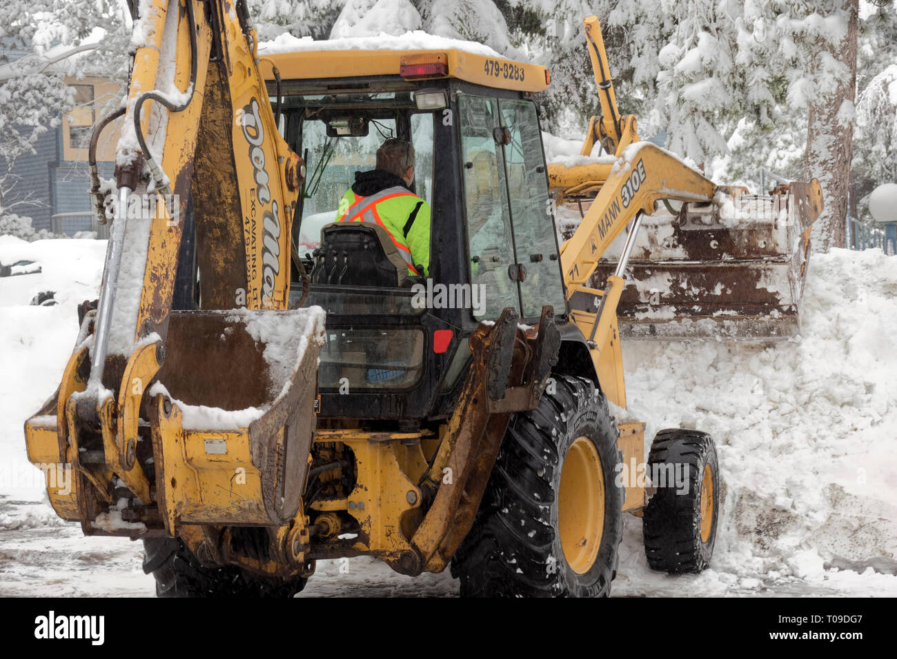 L'uomo la rimozione di neve dal parcheggio dopo la tempesta di neve invernale-Victoria, British Columbia, Canada. Foto Stock