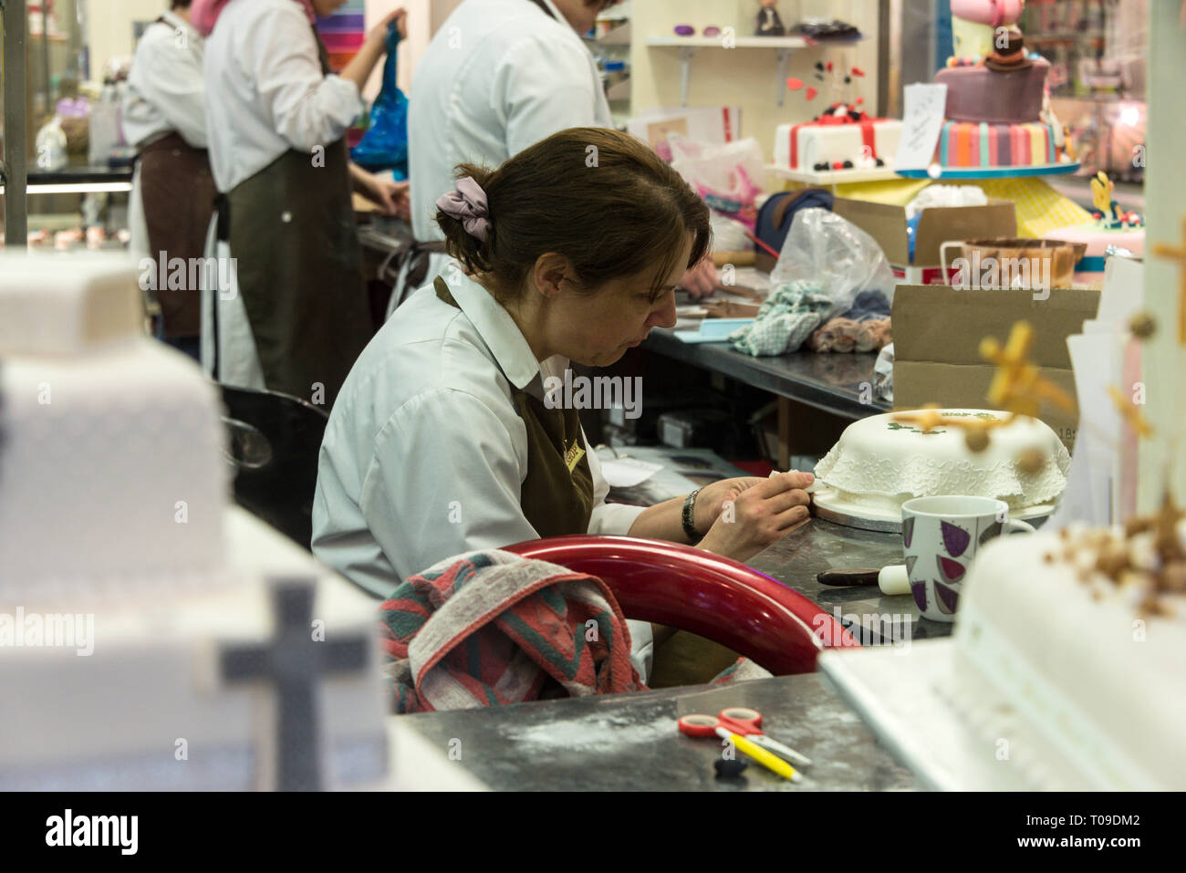 Un pasticciere che decora una torta al mercato sotterraneo Golden Cross di Oxford, Oxfordshire, Gran Bretagna Foto Stock