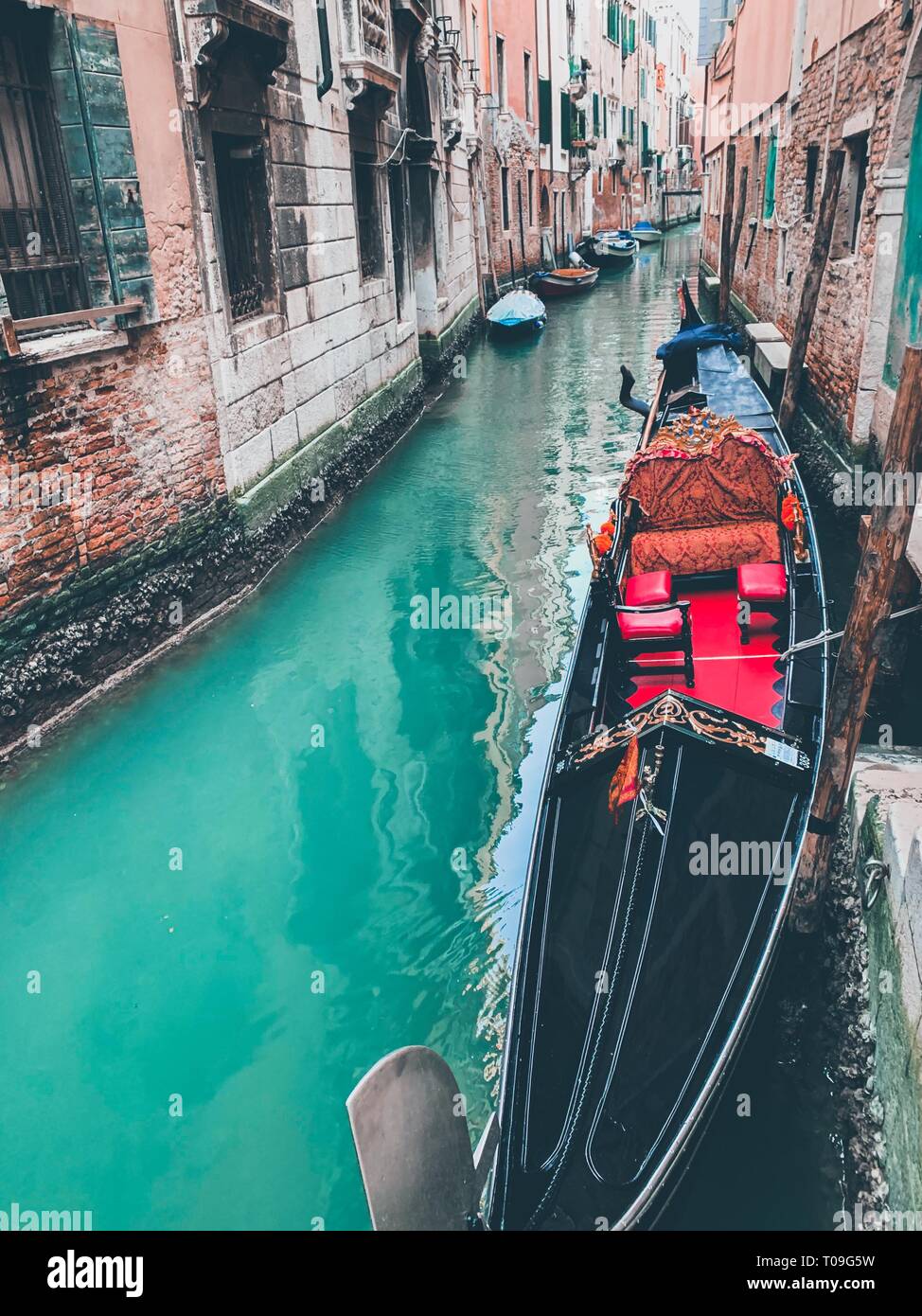 Quadro classico dei canali veneziani con gondola attraverso il canale. Foto Stock