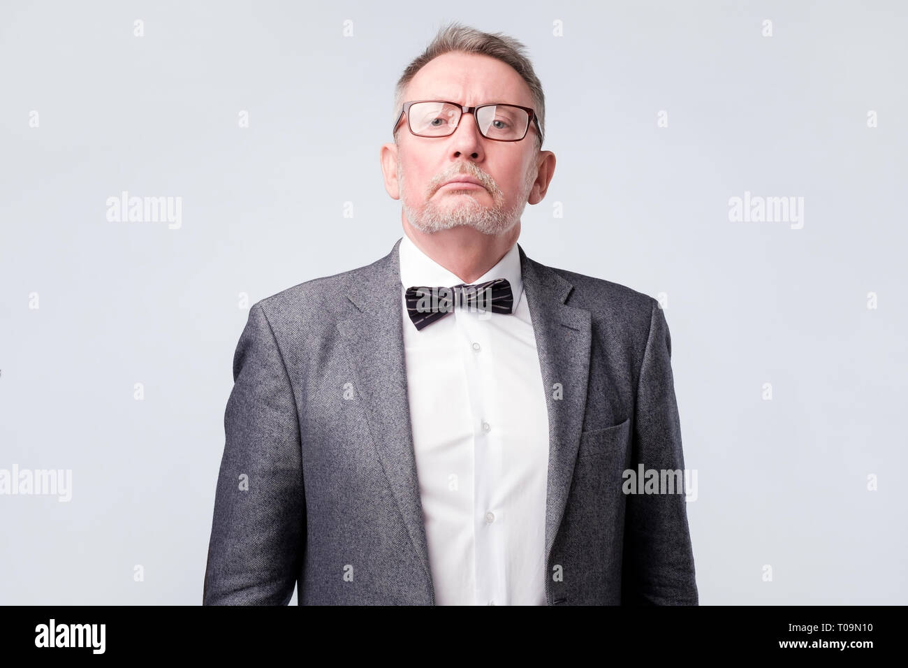 Senior uomo indossare tuta e occhiali alla ricerca seria e fiducioso in telecamera Foto Stock