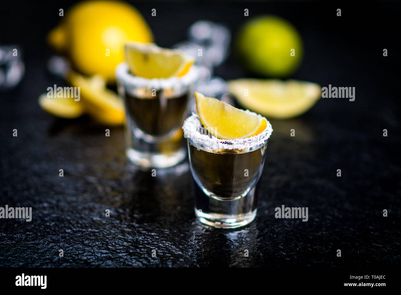 Tradizionale messicano Tequila con limone, sale e il cubo di ghiaccio sulla pietra scura tabella tabella Foto Stock