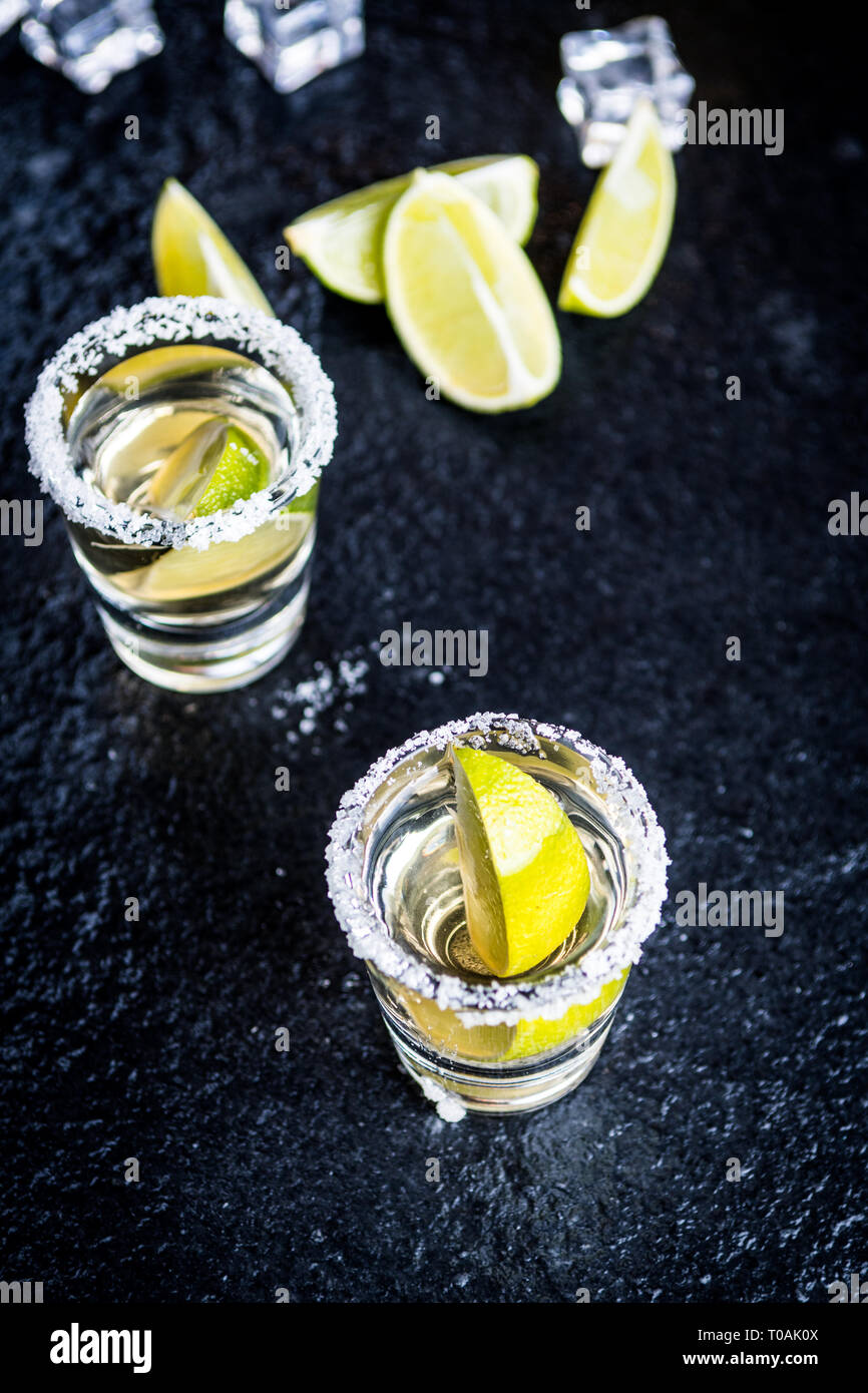 Tradizionale messicano Tequila con limone e sale e cubo di ghiaccio sulla pietra scura tabella tabella Foto Stock