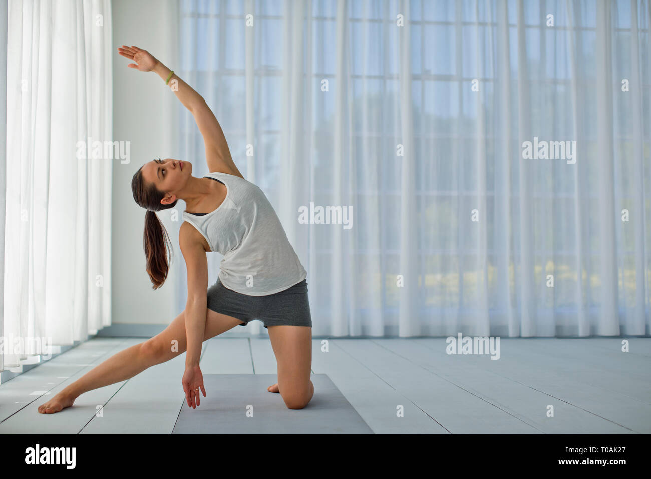 Felice giovane donna stretching le sue braccia e gambe durante la pratica dello yoga. Foto Stock