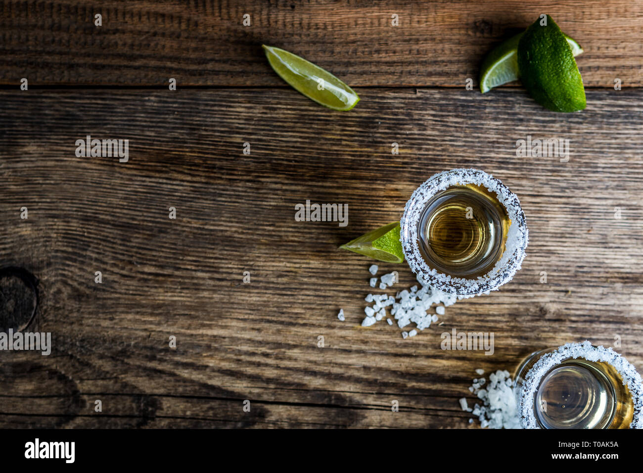Tradizionale messicano alcool bere la tequila con calce e sale e cubo di ghiaccio sul tavolo di legno vista superiore Foto Stock