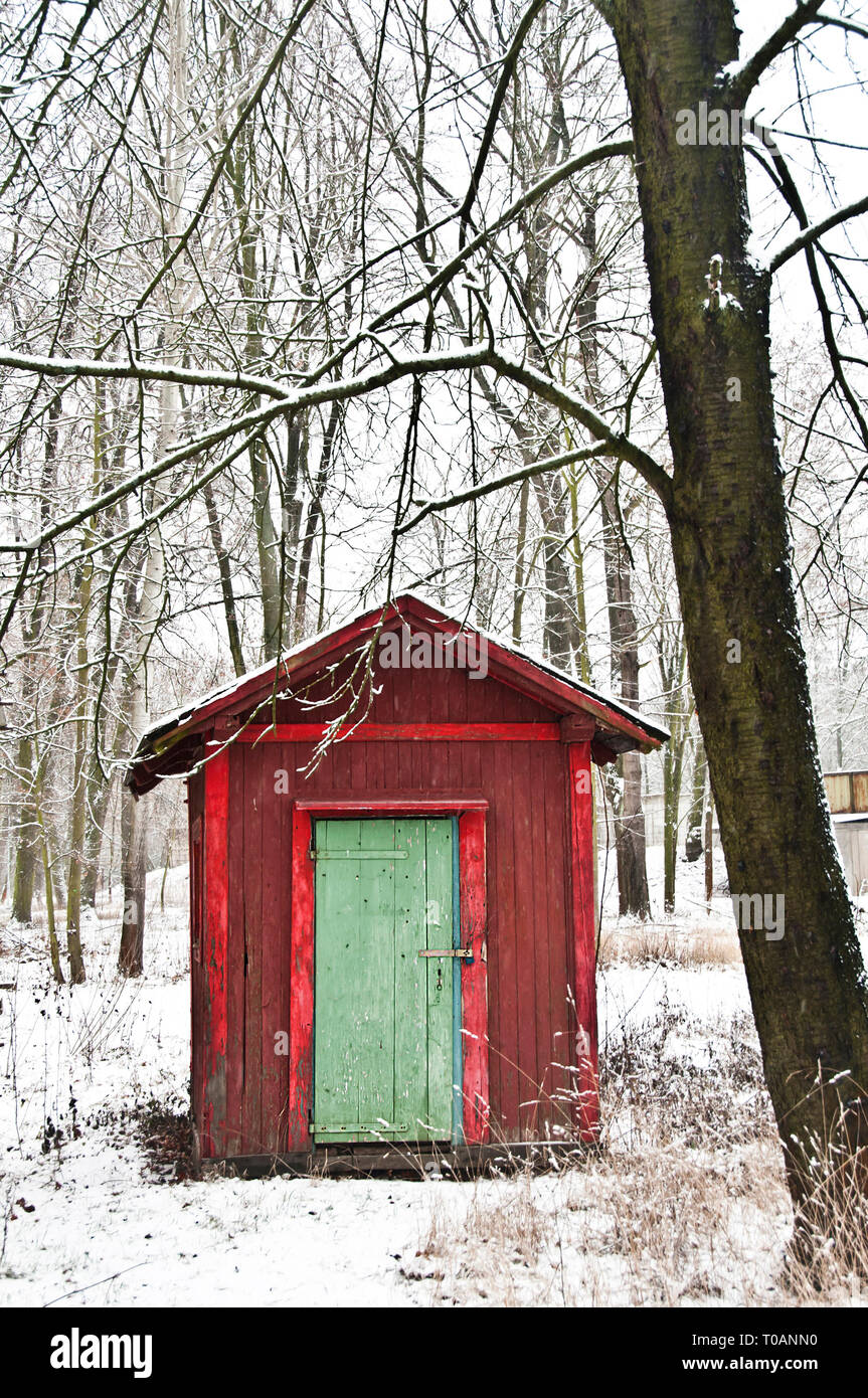 Cabina rosso o la capanna con la porta verde della foresta durante la neve in inverno Foto Stock