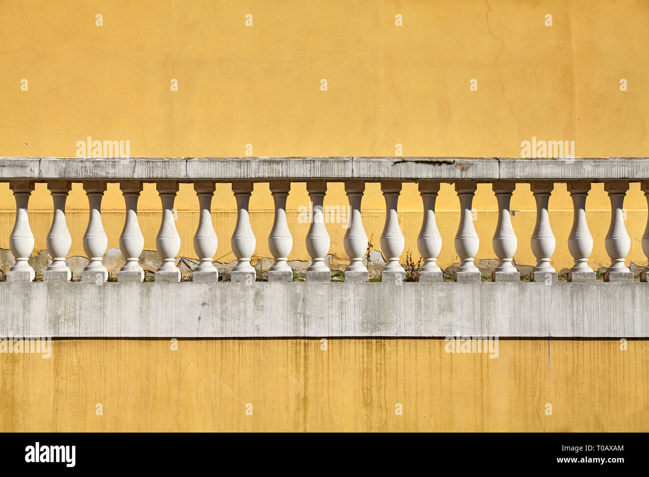 Vecchia balaustra contro la parete gialla, sfondo architettonico. Foto Stock