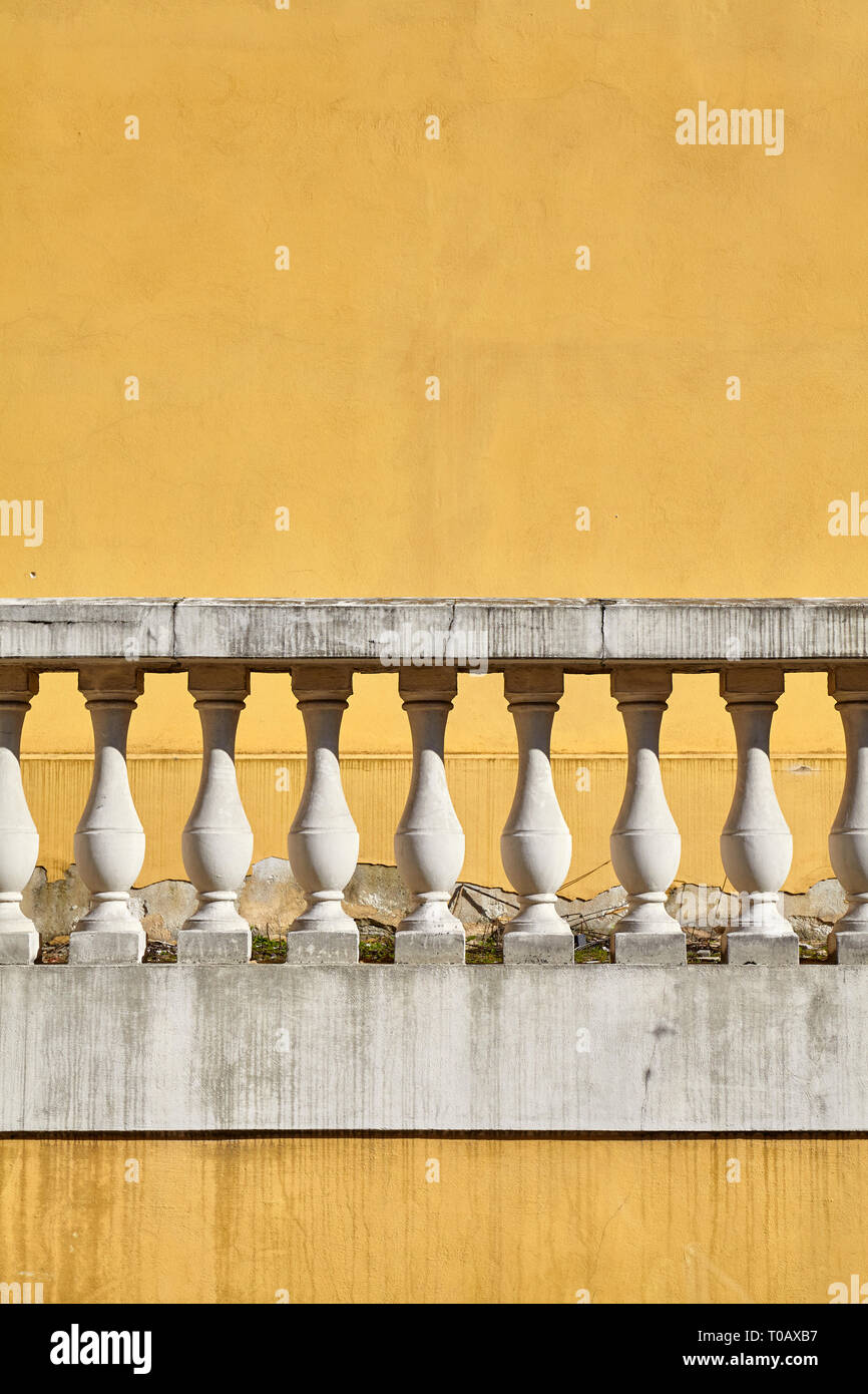 Vecchia balaustra contro la parete gialla, sfondo architettonico. Foto Stock