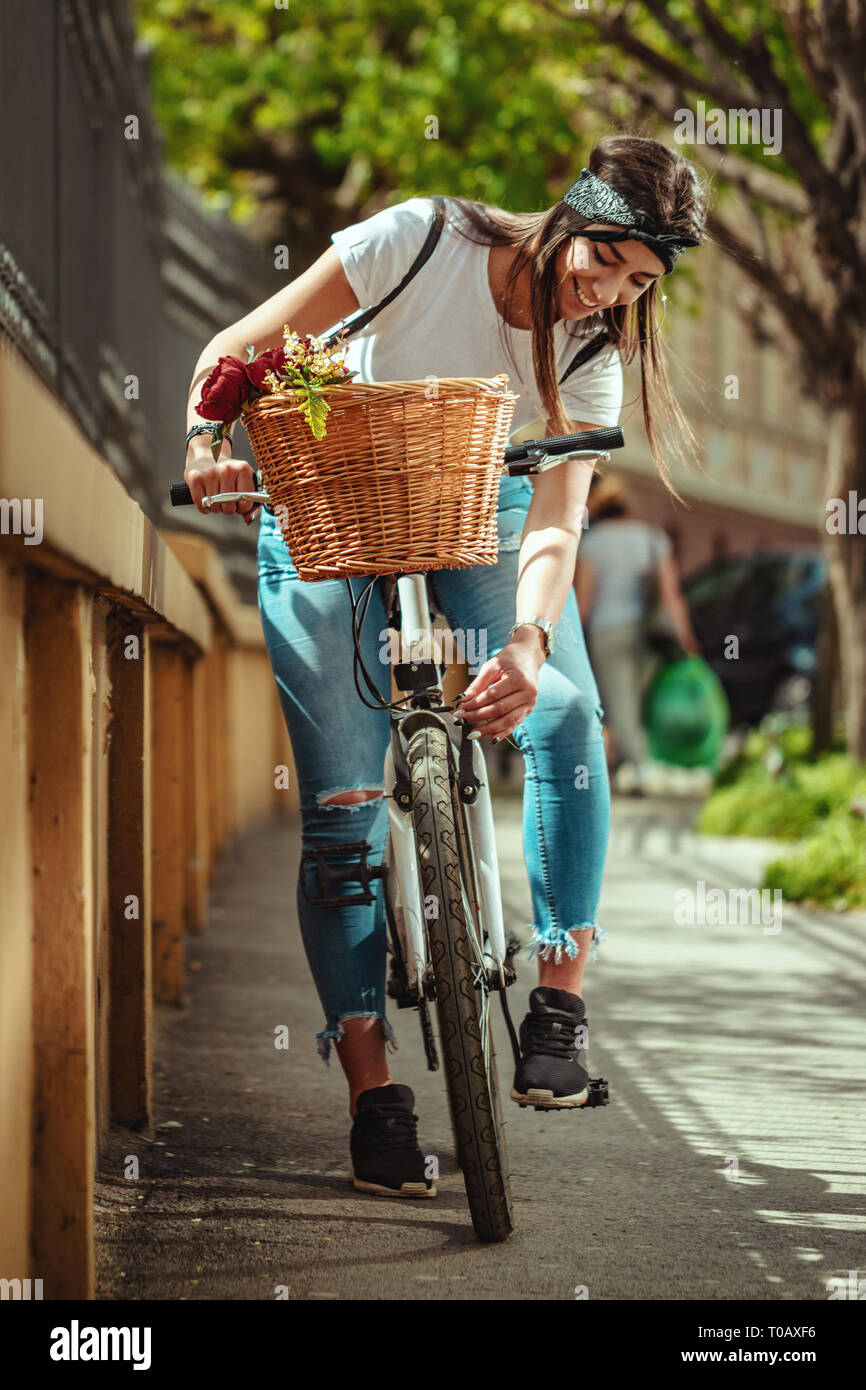 Colpo all'aperto della giovane donna andare in bici lungo la strada della città, e controllo della ruota della bicicletta. Foto Stock