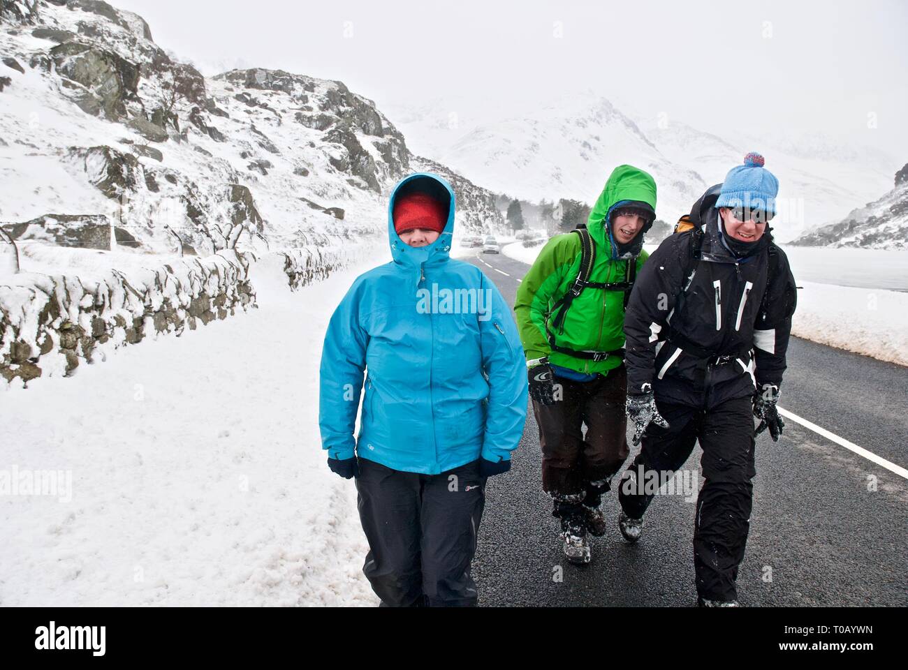 Gli escursionisti a piedi attraverso la valle Ogwen nella neve, in inverno, Snowdonia, Gwynedd, Galles del Nord, Regno Unito Foto Stock