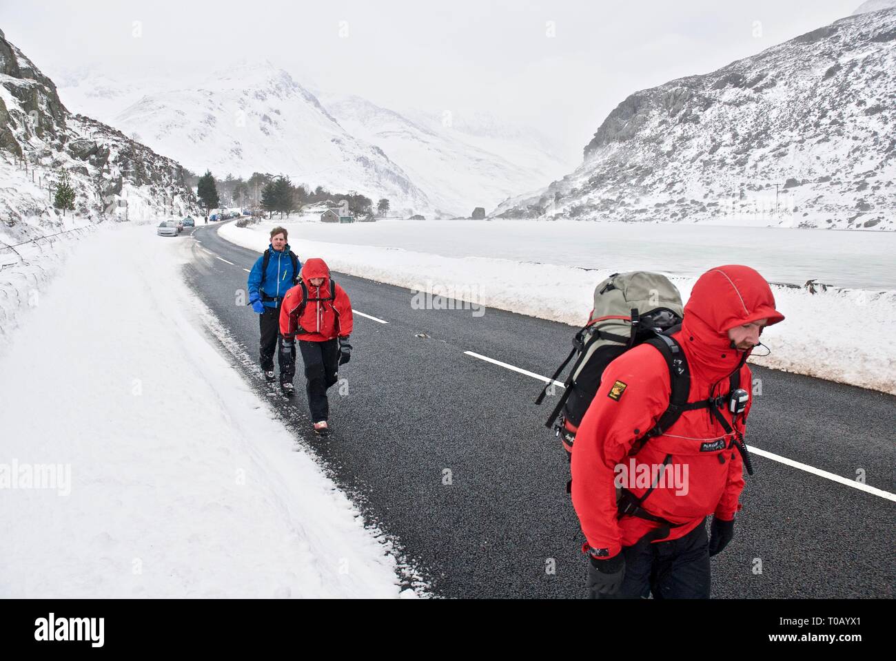 Gli escursionisti a piedi attraverso la valle Ogwen nella neve, in inverno, Snowdonia, Gwynedd, Galles del Nord, Regno Unito Foto Stock