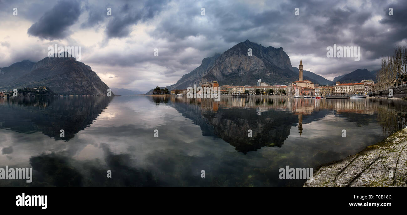 Panorama della città di Lecco riflesse sul lago in una incredibile giorno nuvoloso, Lombardia, Italia Foto Stock