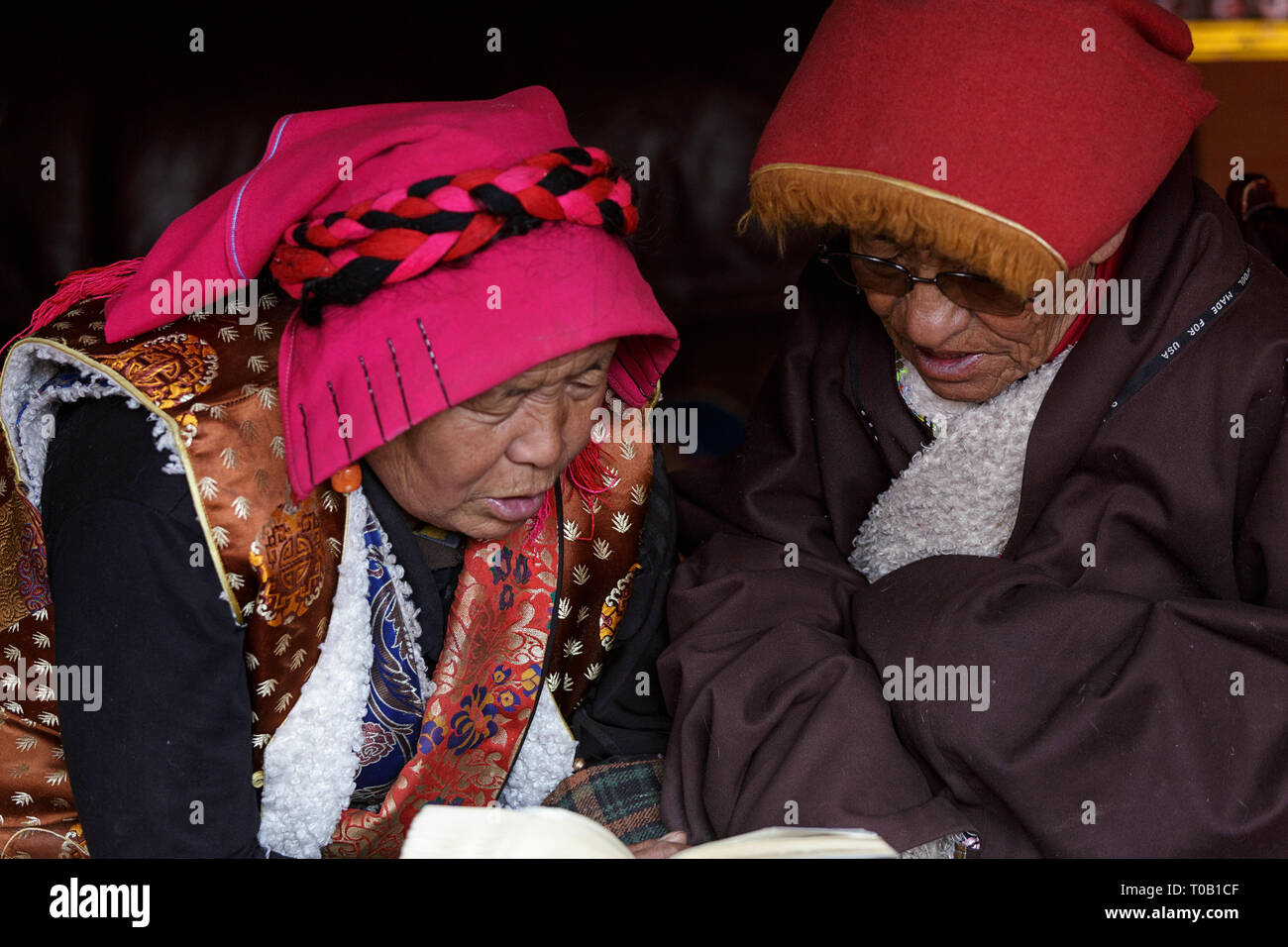 Senior pellegrino tibetano uomo anziano insegnamento donna lettura del pellegrino, Tagong, Sichuan, in Cina Foto Stock
