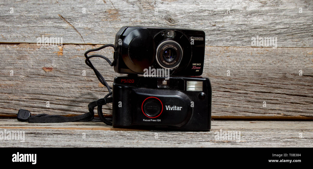 Vecchio fotocamere point and shoot impilata su ogni altra contro uno sfondo di legno. Foto Stock