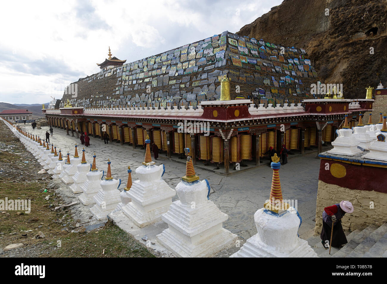 Pellegrini a mani lungo muro di pietra a Ser Gergyo (Ani Gompa) convento, Tagong, Sichuan, in Cina Foto Stock