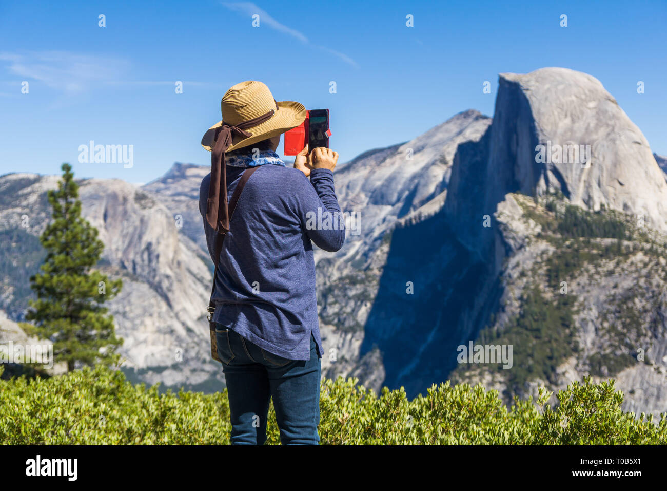 Un turista a scattare foto di mezza cupola sul suo smartphone nel Parco Nazionale di Yosemite in California Foto Stock