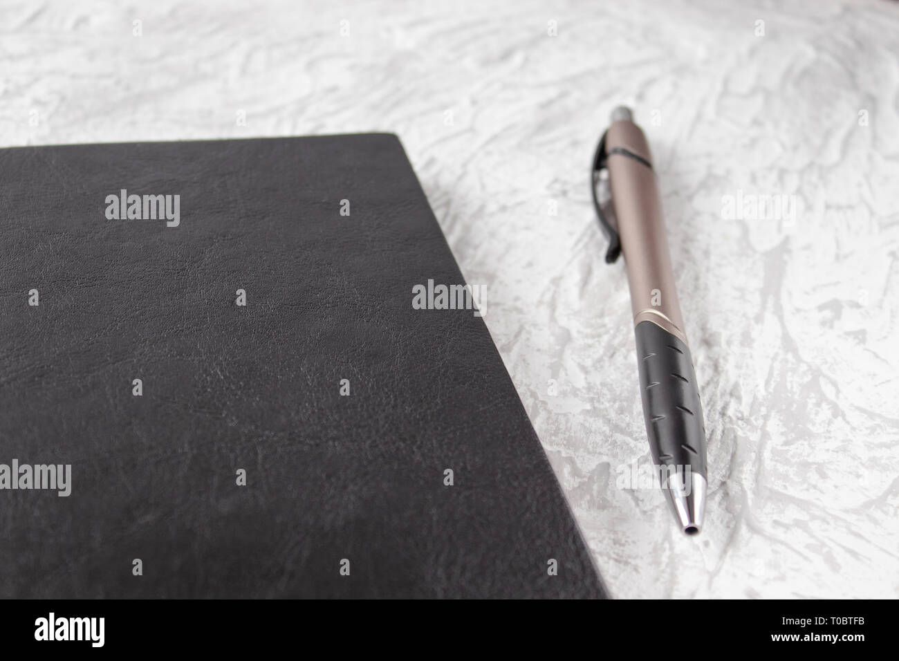 Vista superiore del notebook nero e le penne in bianco su sfondo tabella per la disposizione. Vi è un posto per il vostro testo. Foto Stock