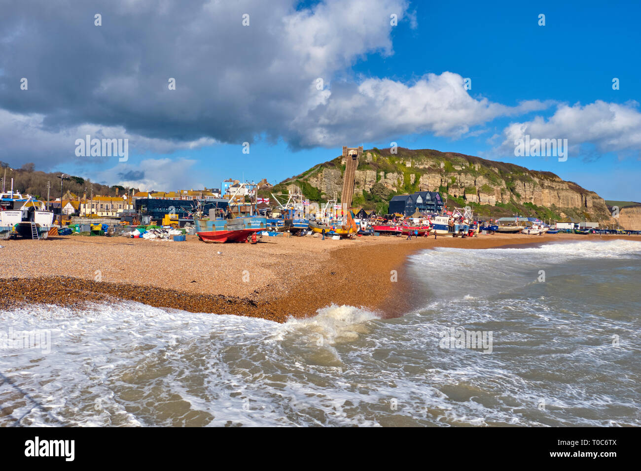 Hastings, East Sussex, Regno Unito. Il 10 marzo 2019. Hastings barche da pesca tirato su in alto sulla spiaggia di Stade al di fuori della portata delle onde pilotato da gale force venti Foto Stock