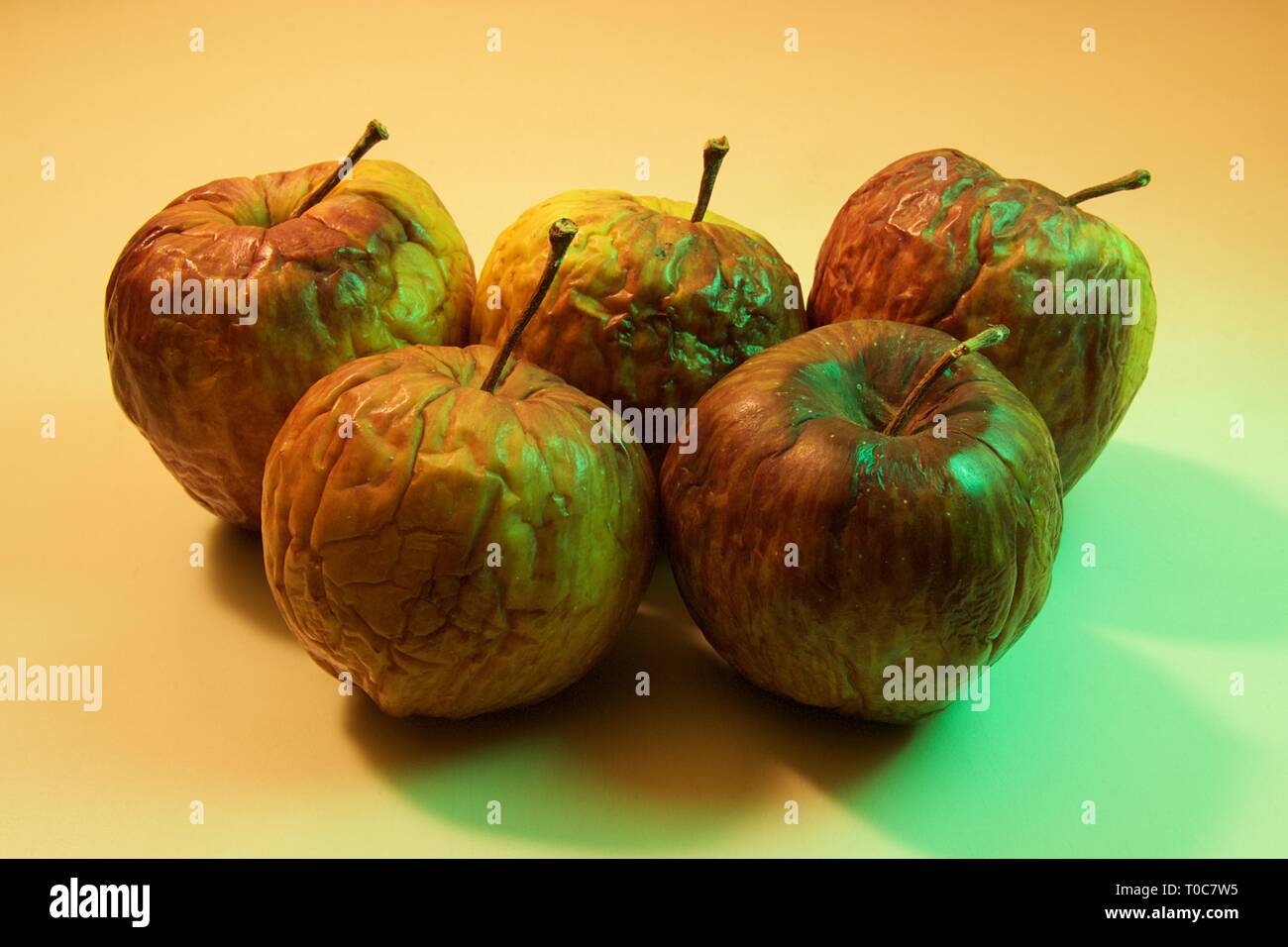 Chiudere fino a cinque mele marce isolate su sfondo colorato Foto Stock