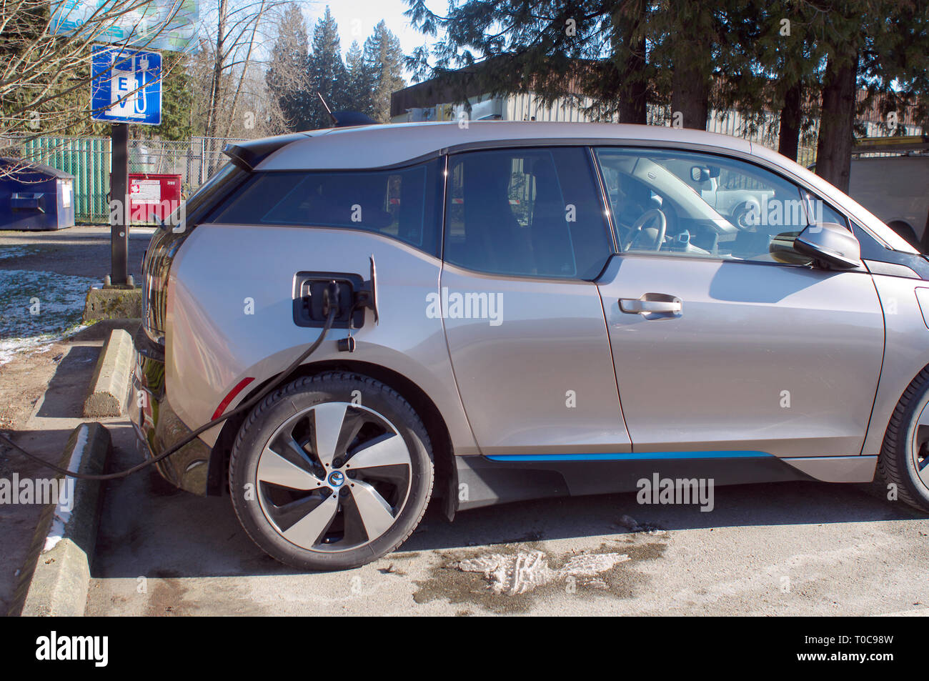 Auto elettrica alla stazione di carica che mostra segni di EV in background. Foto Stock