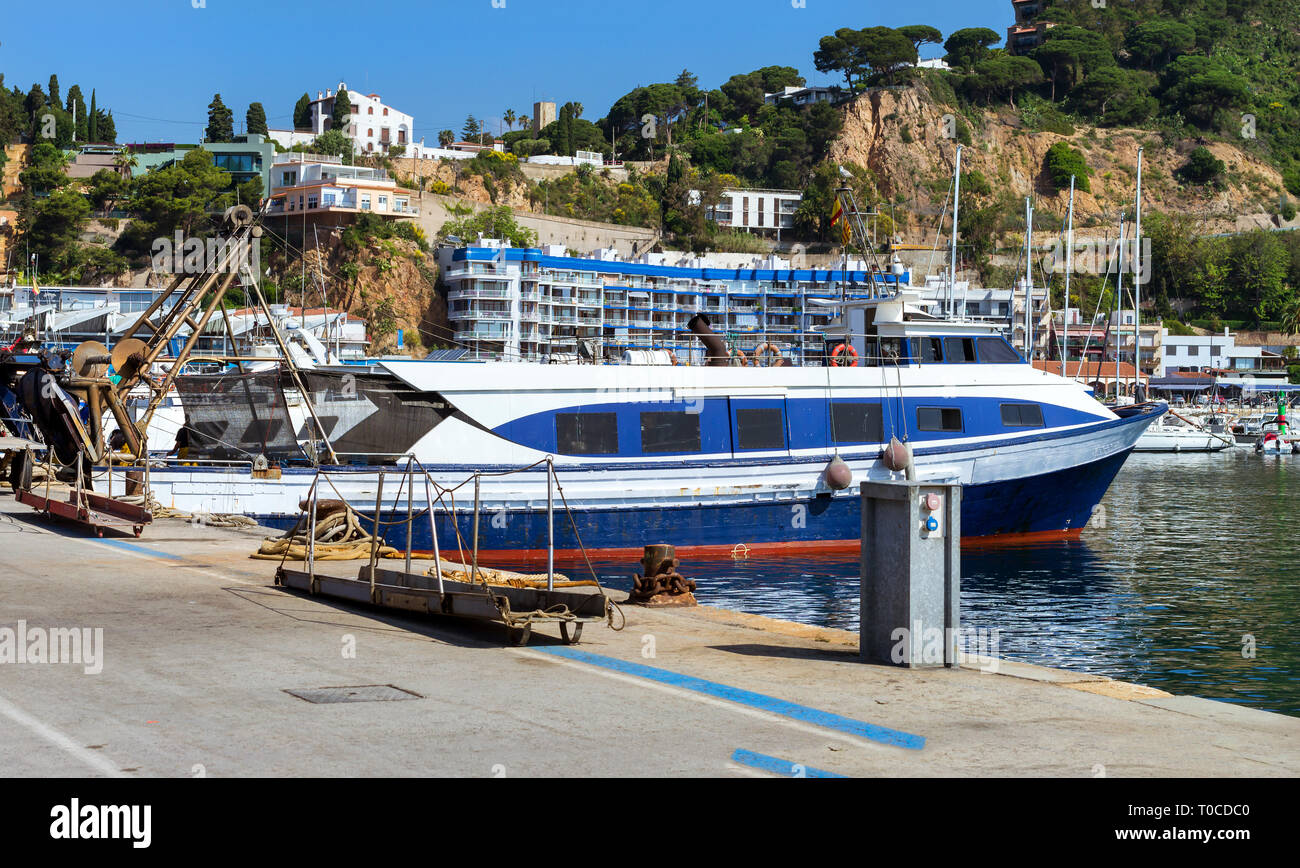 Barca da pesca e yacht ormeggiati al molo nel porto Blanes. Lo scarico delle catture di pesce di mare, ostriche, calamari, delicatezze di mare. Asta del pesce per i grossisti e i periodi di riposo Foto Stock