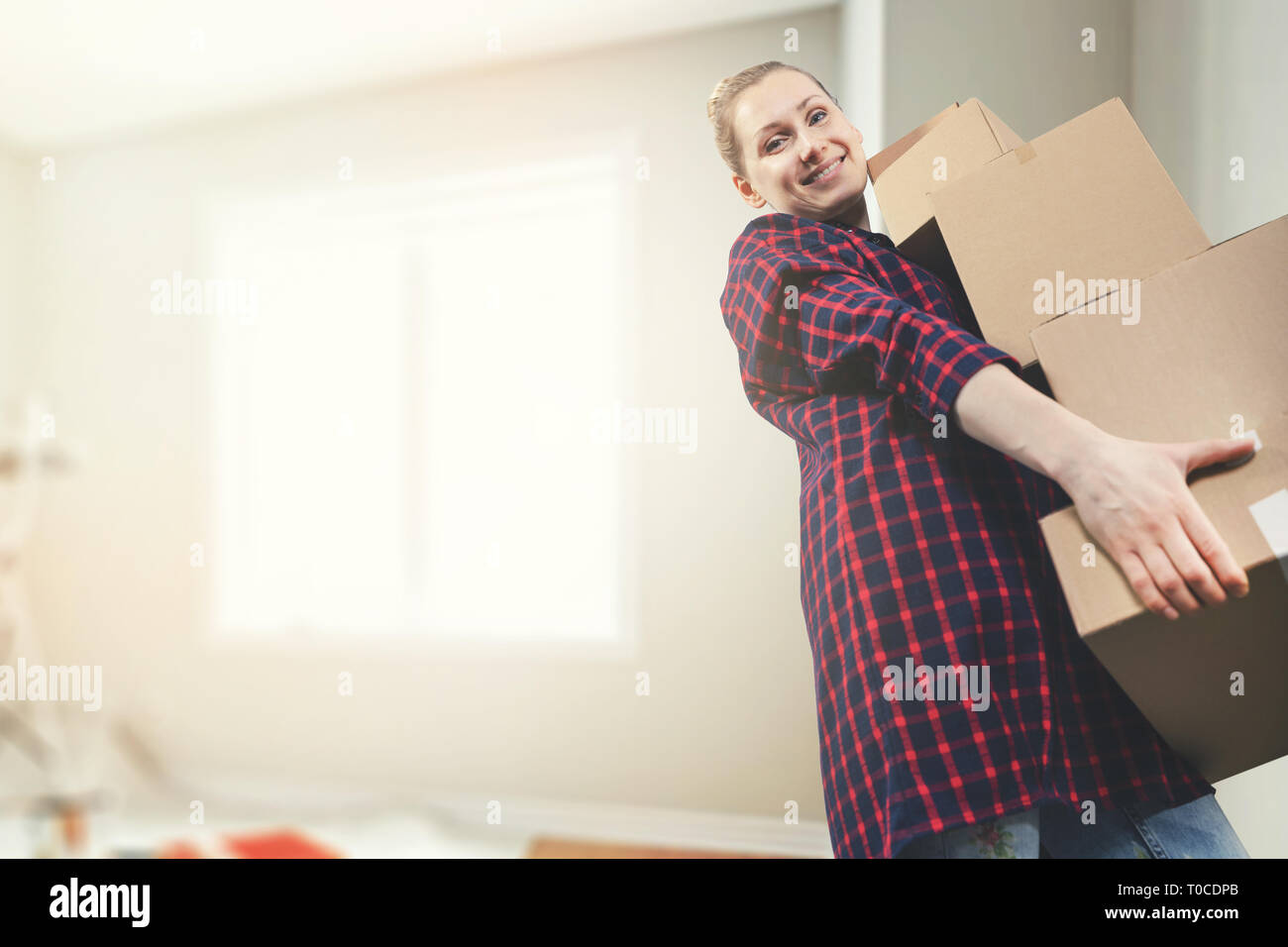 Traslocare in una nuova casa - sorridente giovane donna che trasportano le caselle. spazio copia Foto Stock