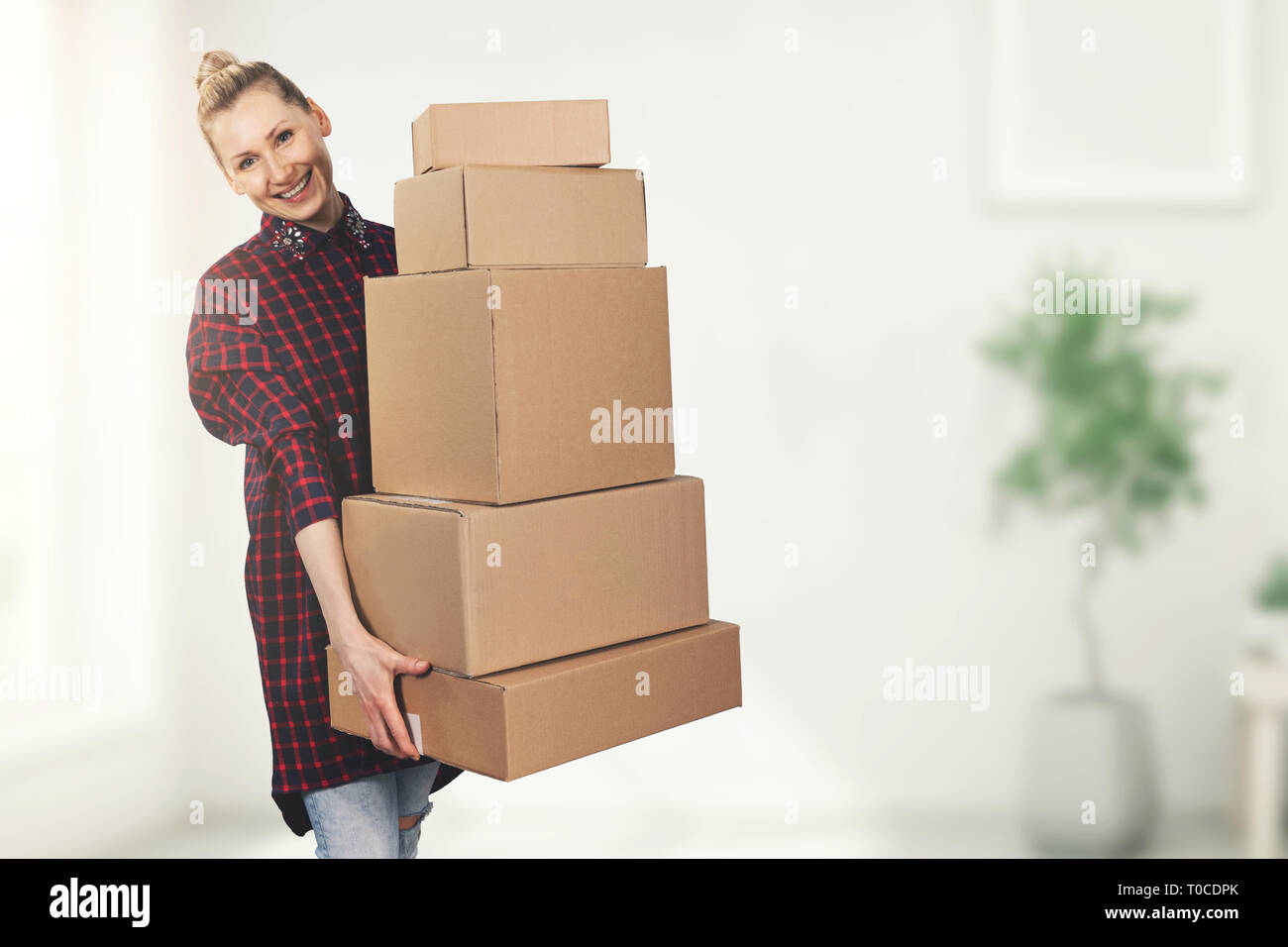 Donna felice in piedi nella nuova casa con scatole in mani Foto Stock