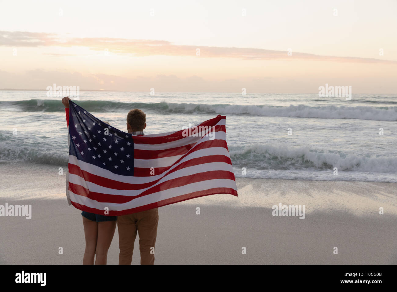 Giovani caucasici giovane azienda bandiera americana a beach Foto Stock