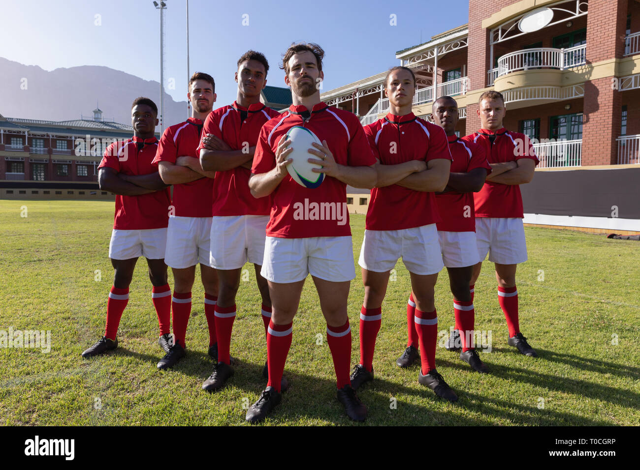 Team dei maschi di giocatori di rugby in piedi con la palla da rugby nel rugby ground Foto Stock