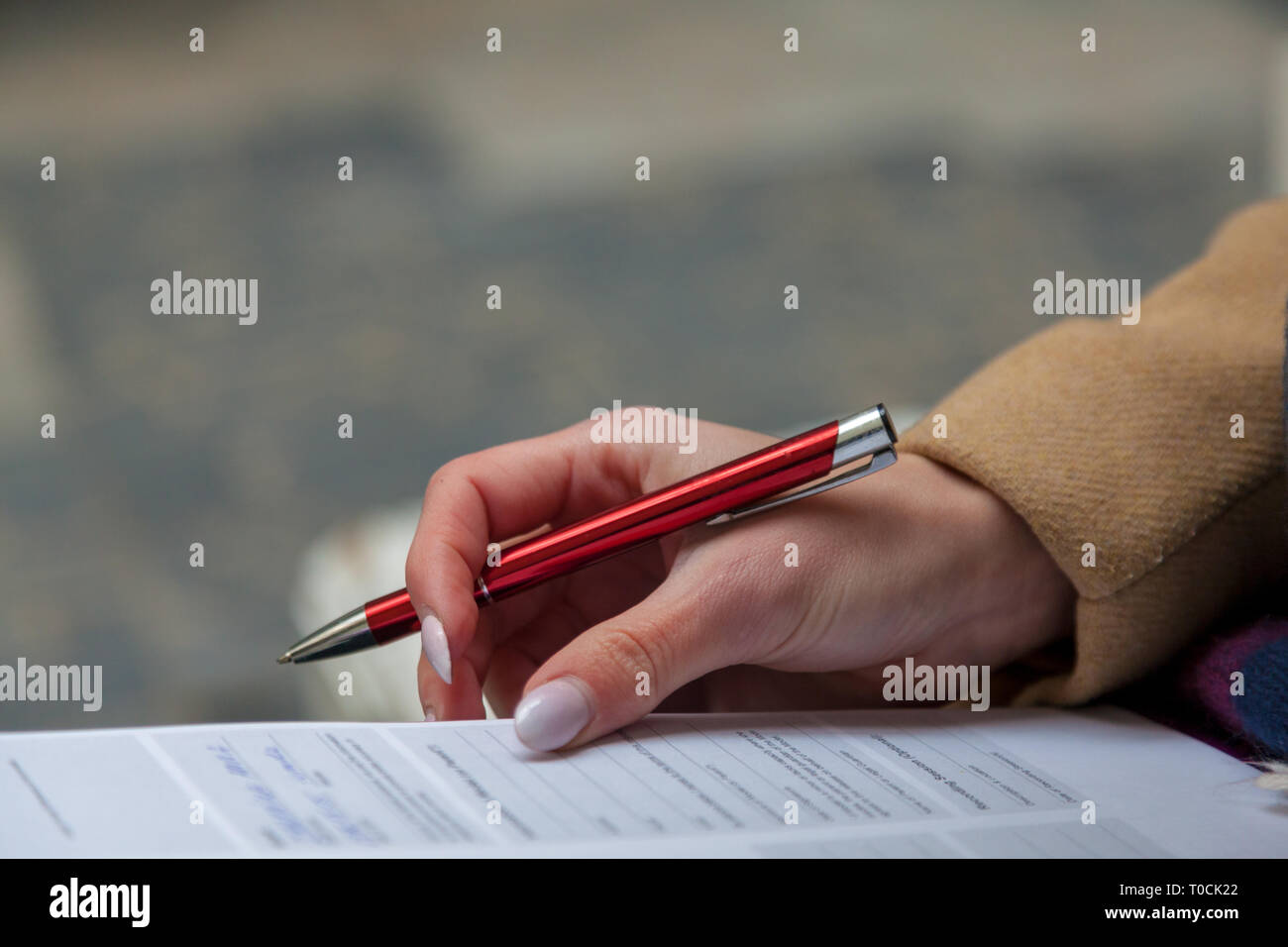 Una immagine di una mano e di una penna della compilazione di un modulo. Donna mani con manicure pastello con la penna. L'occupazione. Documento firma Foto Stock