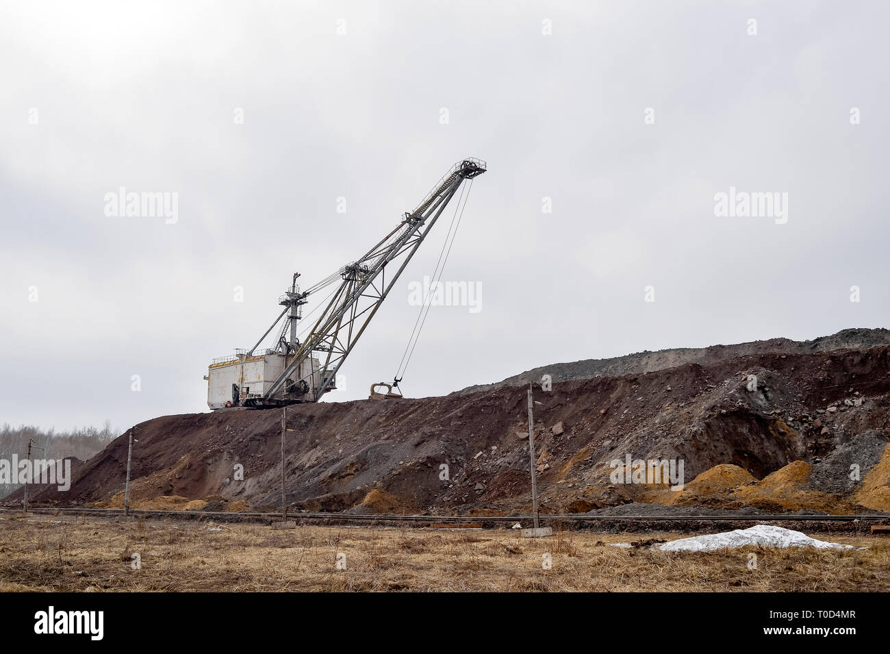 Grande escavatore a piedi in previsione del materiale rotabile il trasporto di sovraccaricare per lo stoccaggio in discariche. Paesaggio industriale dopo la distruzione di n Foto Stock